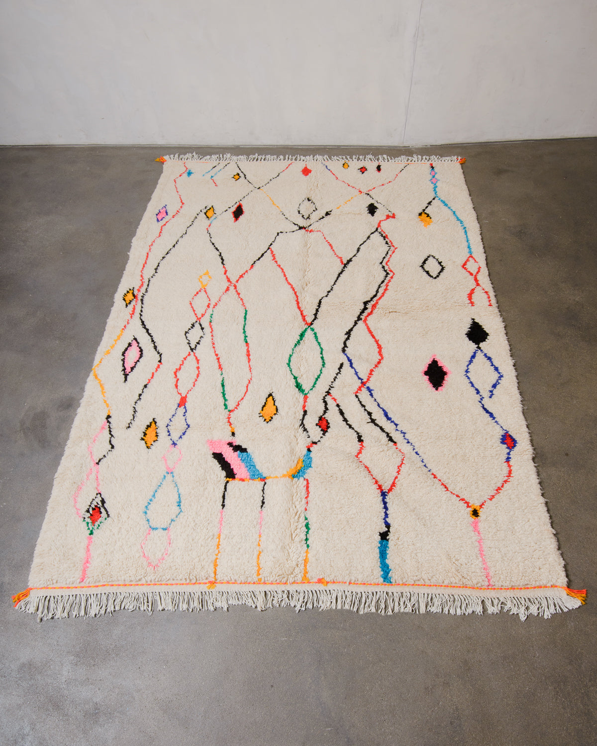 Berberlin Azilal rug made of fluffy wool and cotton, laying flat on a concrete floor.
